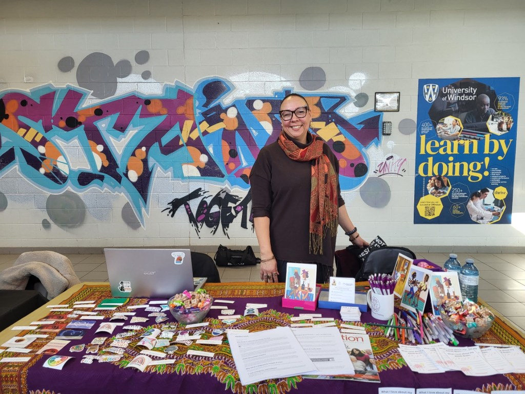 Faelyne Templer standing at the Path & Purpose vendor table, smiling.