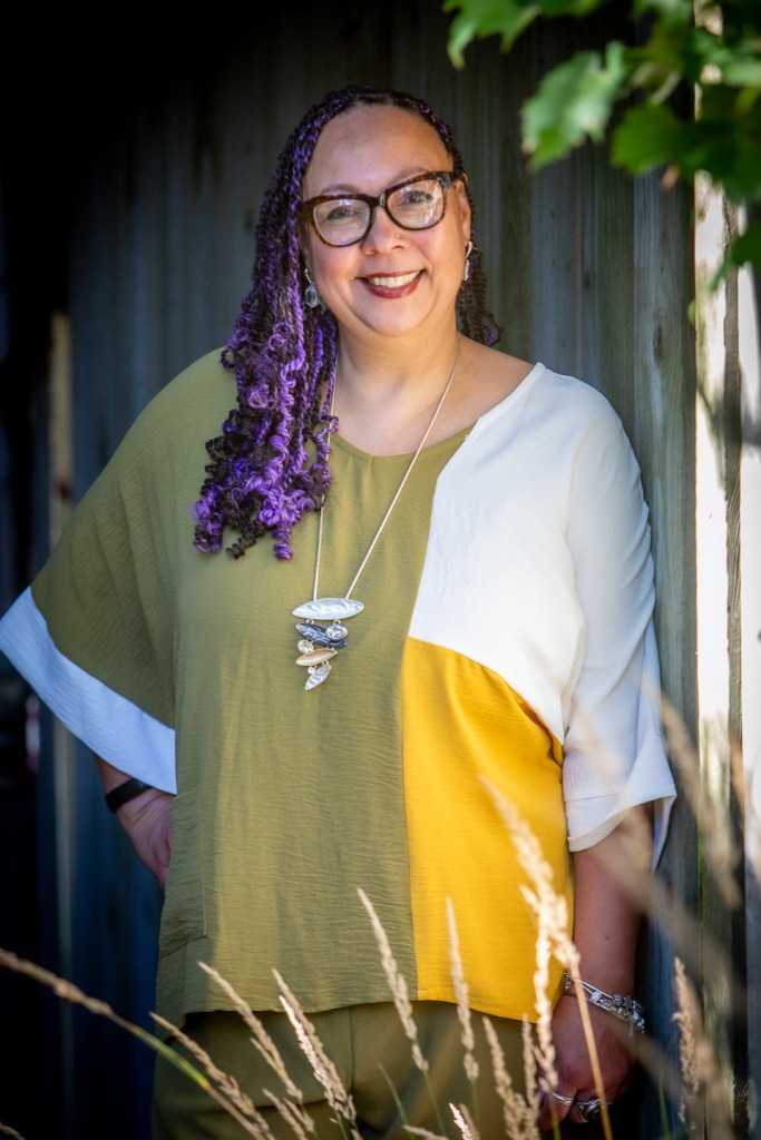 Faelyne standing in a doorway framed by leaves and tall grasses.